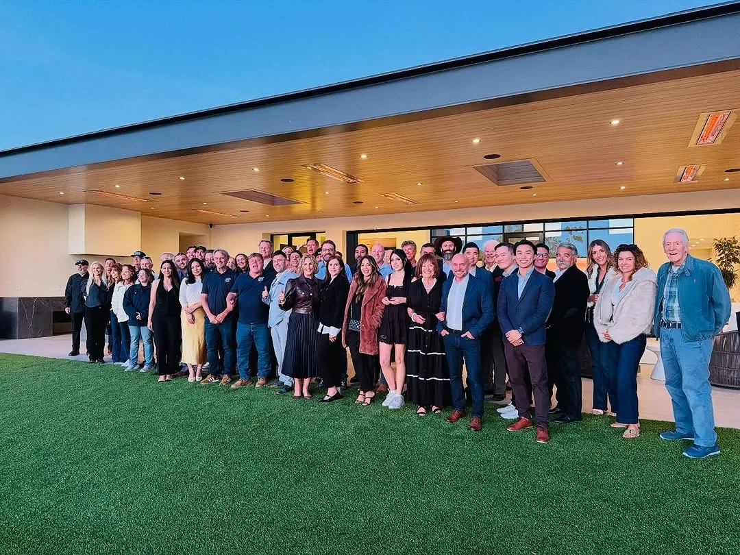 Watch-party guests posing together beneath a terrace